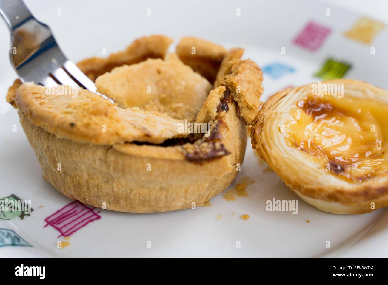 a Fork tuck into Chicken pie with egg tart as side dish, UK, Stock Photo