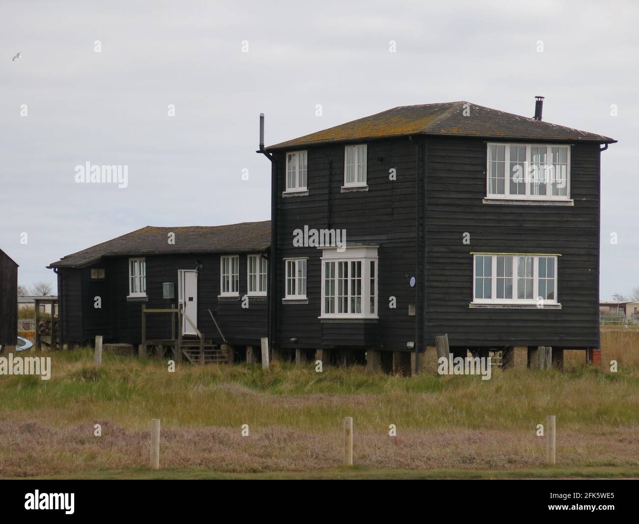 The traditional black timber weatherboarding on a building on stilts by the quayside at Walberswick on the east coast of Suffolk. Stock Photo