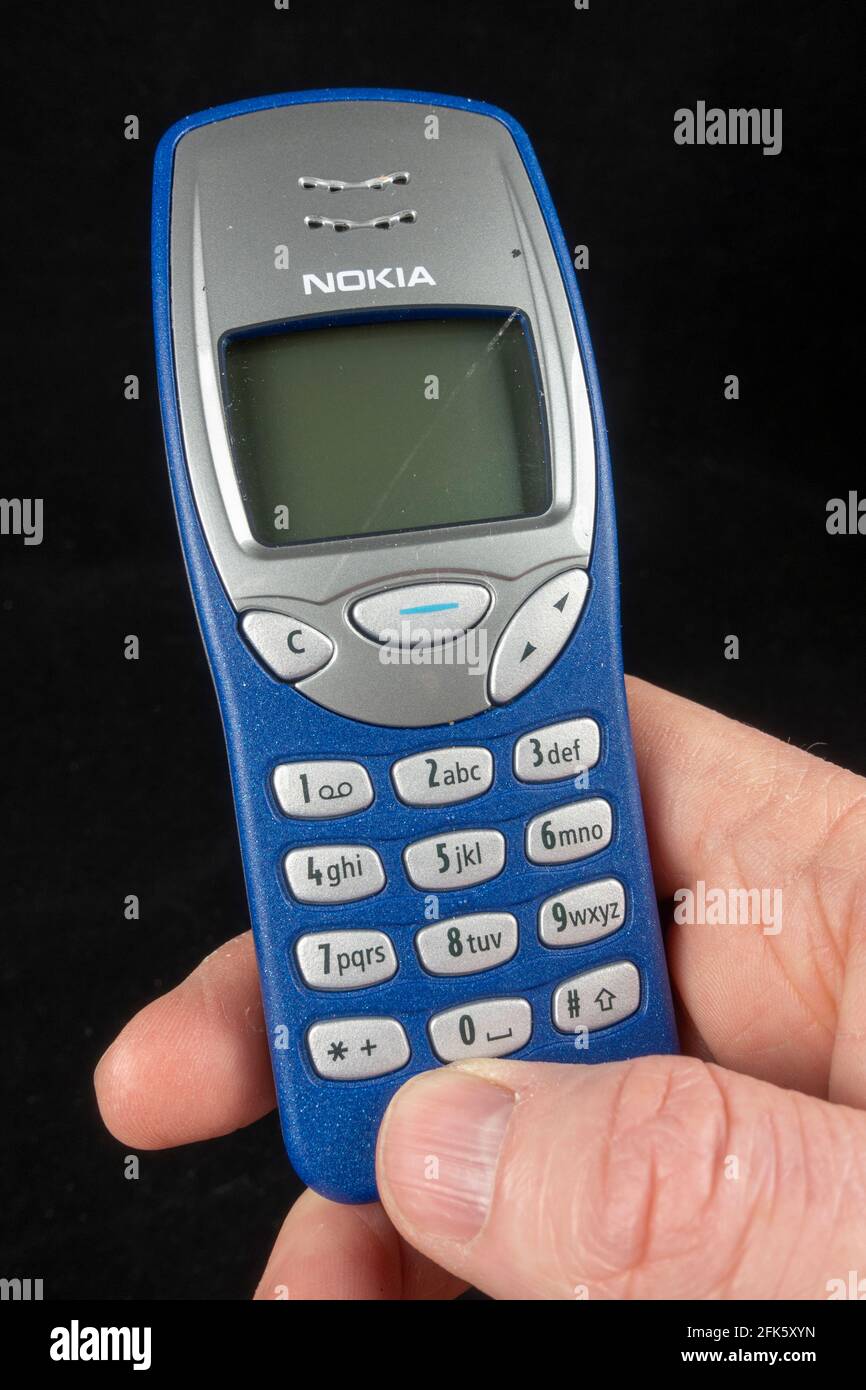 A man holding an Orange Nokia 3210e phone (the Nokia 3210e was originally released in 1999), Stock Photo