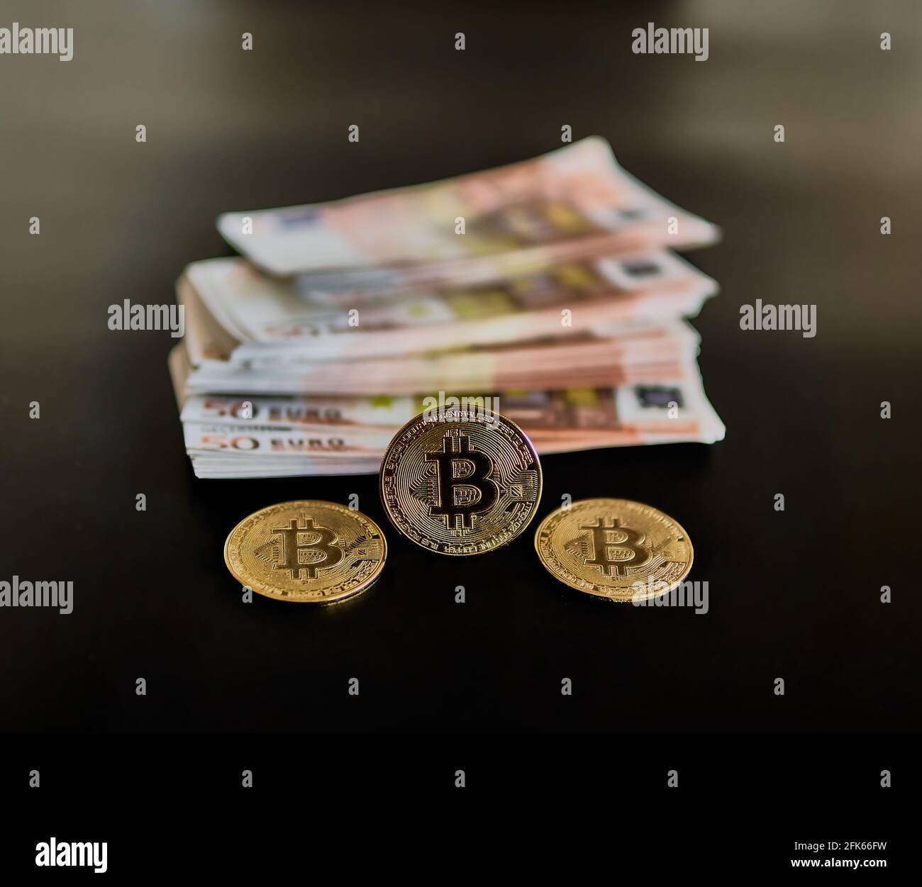 Three Bitcoin coins, along with several 50 euro bills. Concept of power, wealth, economy, Btc, anonymity. Selective focus. Stock Photo