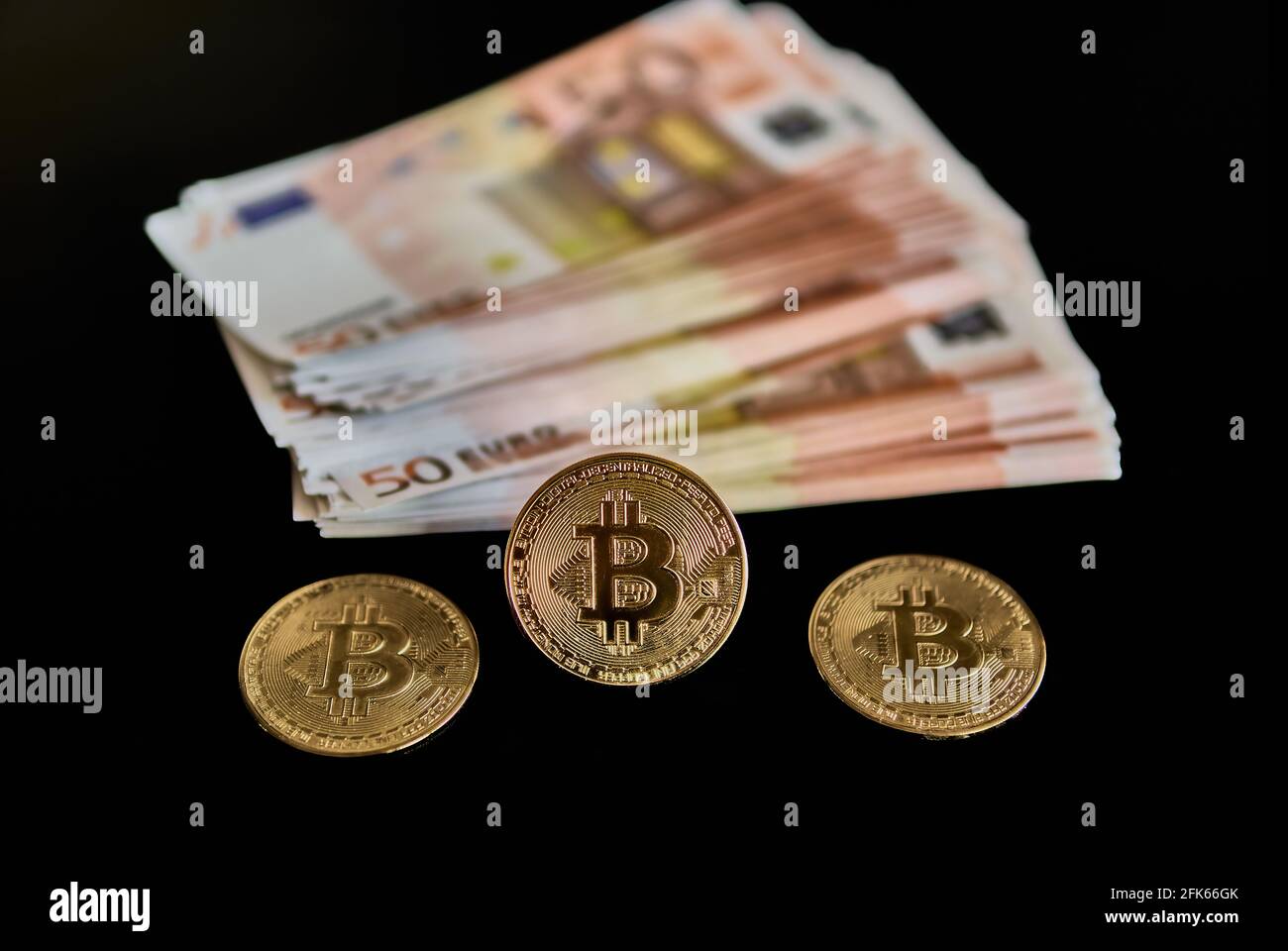 Top view of Bitcoin coins, next to 50 euro banknotes, on black background. Concept of power, economics, money, anonymity, exchange, Btc. Selective focus. Stock Photo