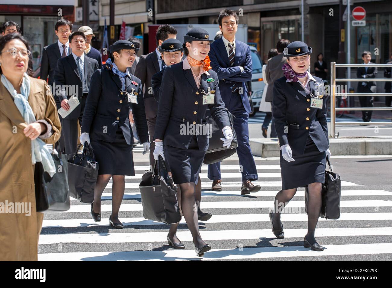 Four female off duty flight attendants wearing uniforms crossing busy zebra crossing in Ginza, Tokyo, Japan Stock Photo