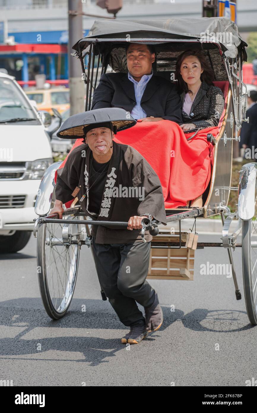 Rickshaw driver/puller pokes tongue at camera as he pulls rickshaw  containing large Japanese male and his attractive wife, Asakusa, Tokyo,  Japan Stock Photo - Alamy