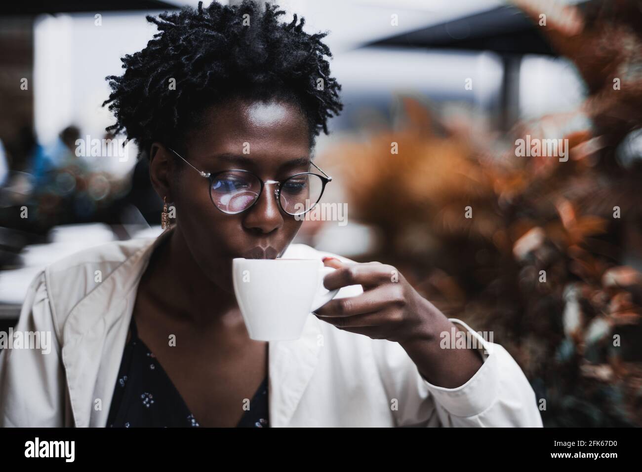 Portrait of a young glamorous black female in classy spectacles drinking a  hot tea in a street cafe; ravishing African woman in glasses drinking a del  Stock Photo - Alamy