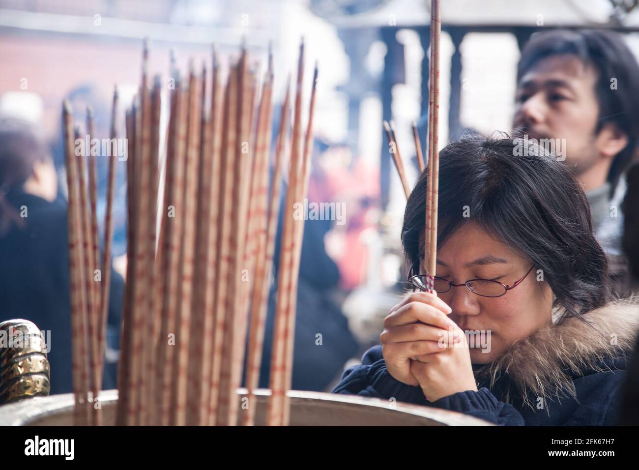 Japanese female burning incense stick whilst praying at Kanteibyo