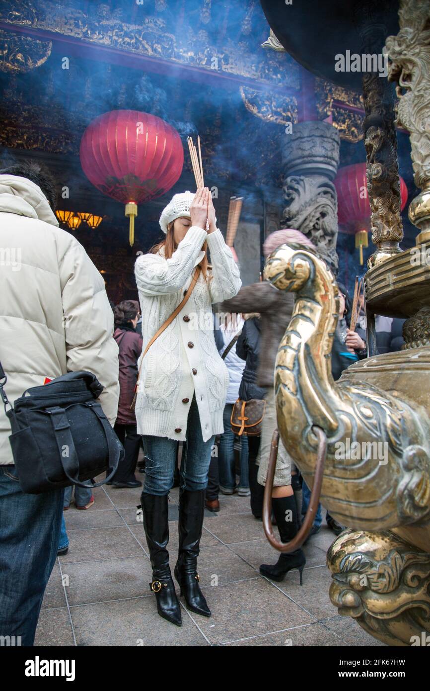 Japanese female burns incense stick whilst praying at Kanteibyo Temple, Chinatown, Yokohama, Japan Stock Photo