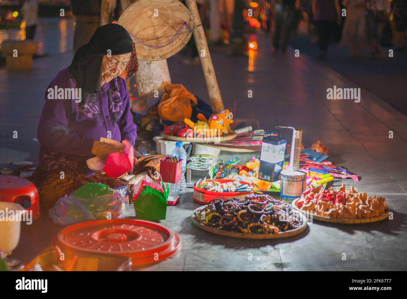 Elderly Vietnamese lady selling colourful floating lanterns and other tourist gifts, Old Town, Hoi An, Vietnam Stock Photo