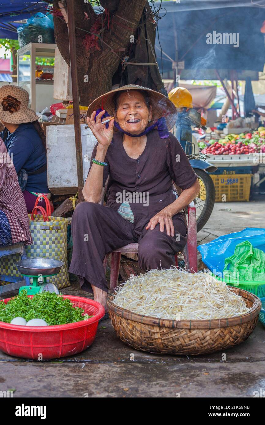 Vietnamese female market trader smoking cigarette smiles at camera with  betel nut stained teeth, Hoi An, Vietnam Stock Photo