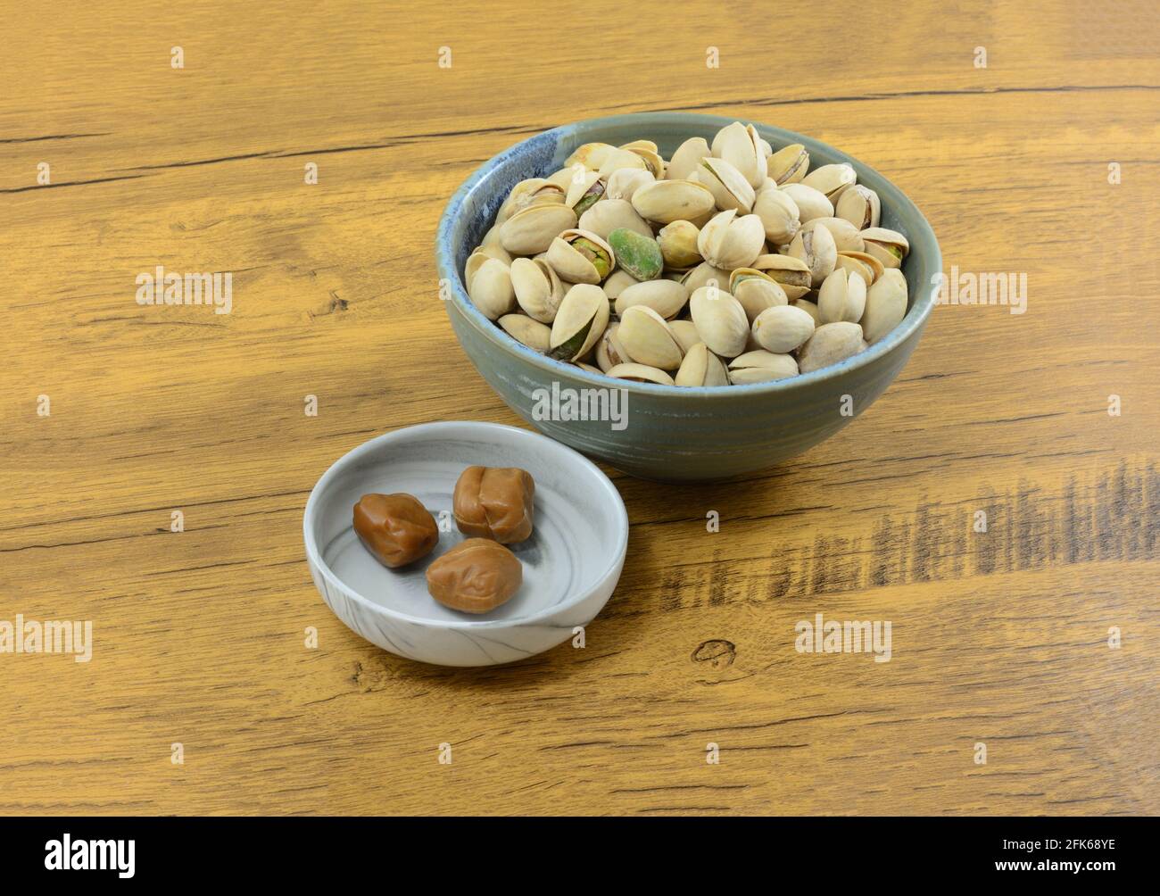 Pistachio toffee candy in candy dish with pistachio nuts in shells in