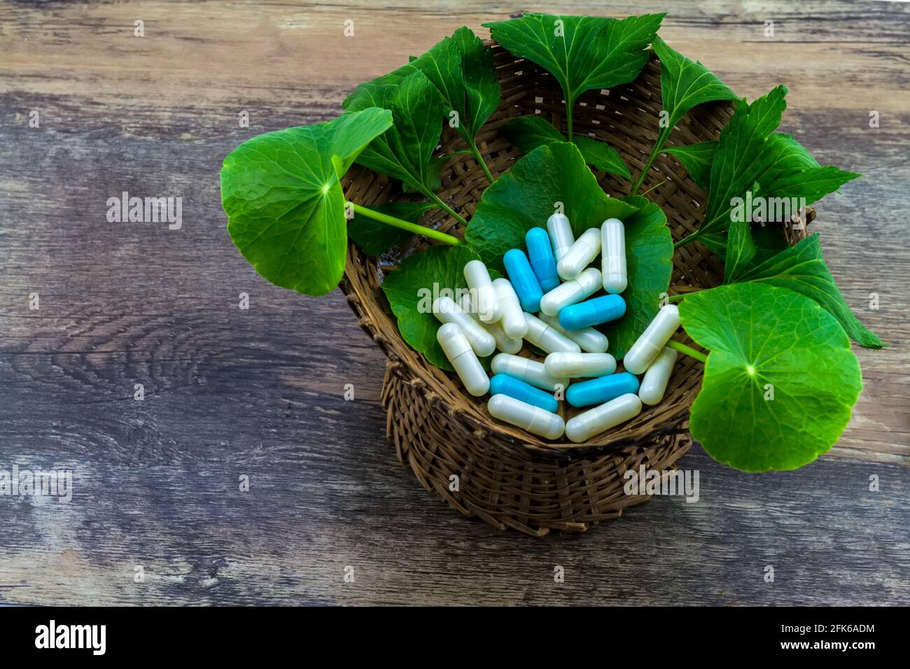 Colorful of pill and green leaf of White mugwort plant (Artemisia lactiflora) with Green Asiatic Pennywort (Centella asiatica ) in bamboo basket on gr Stock Photo
