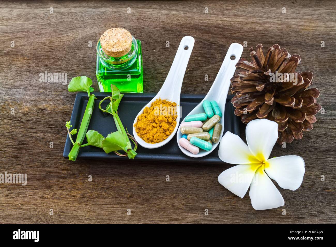 Spa herbal (white frangipani flowers, turmeric powder in white spoon ,pill,Cissus Quadrangularis Linn,pine,Aloe vera essential oil ) on wooden backgro Stock Photo