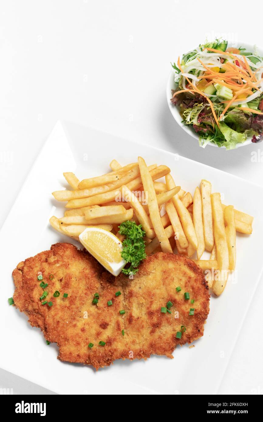 german breaded pork schnitzel with french fries on white studio background Stock Photo