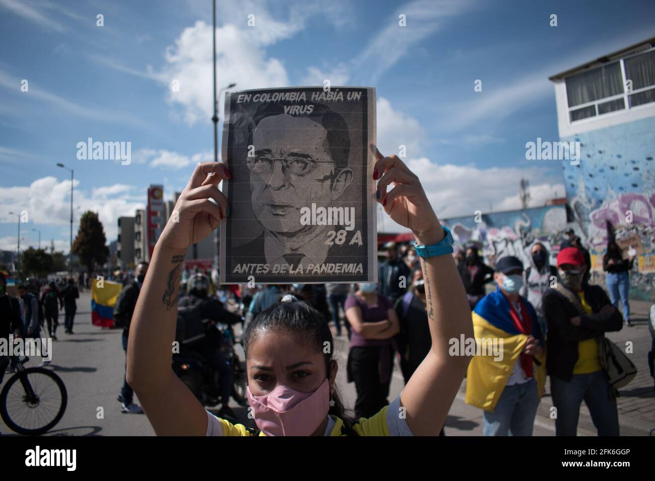 Bogota, Cundinamarca, Colombia. 28th Apr, 2021. A demonstrator holds a sign that reads 'In Colombia there was a virus before the pandemic' with an image of former president Alavaro Uribe Velez demonstrations rise against the tributary reform of president Ivan Duque on April 28, 2021, demonstrations rised to clashes between police and demonstrators. Credit: Daniel Santiago Romero Chaparro/LongVisual/ZUMA Wire/Alamy Live News Stock Photo