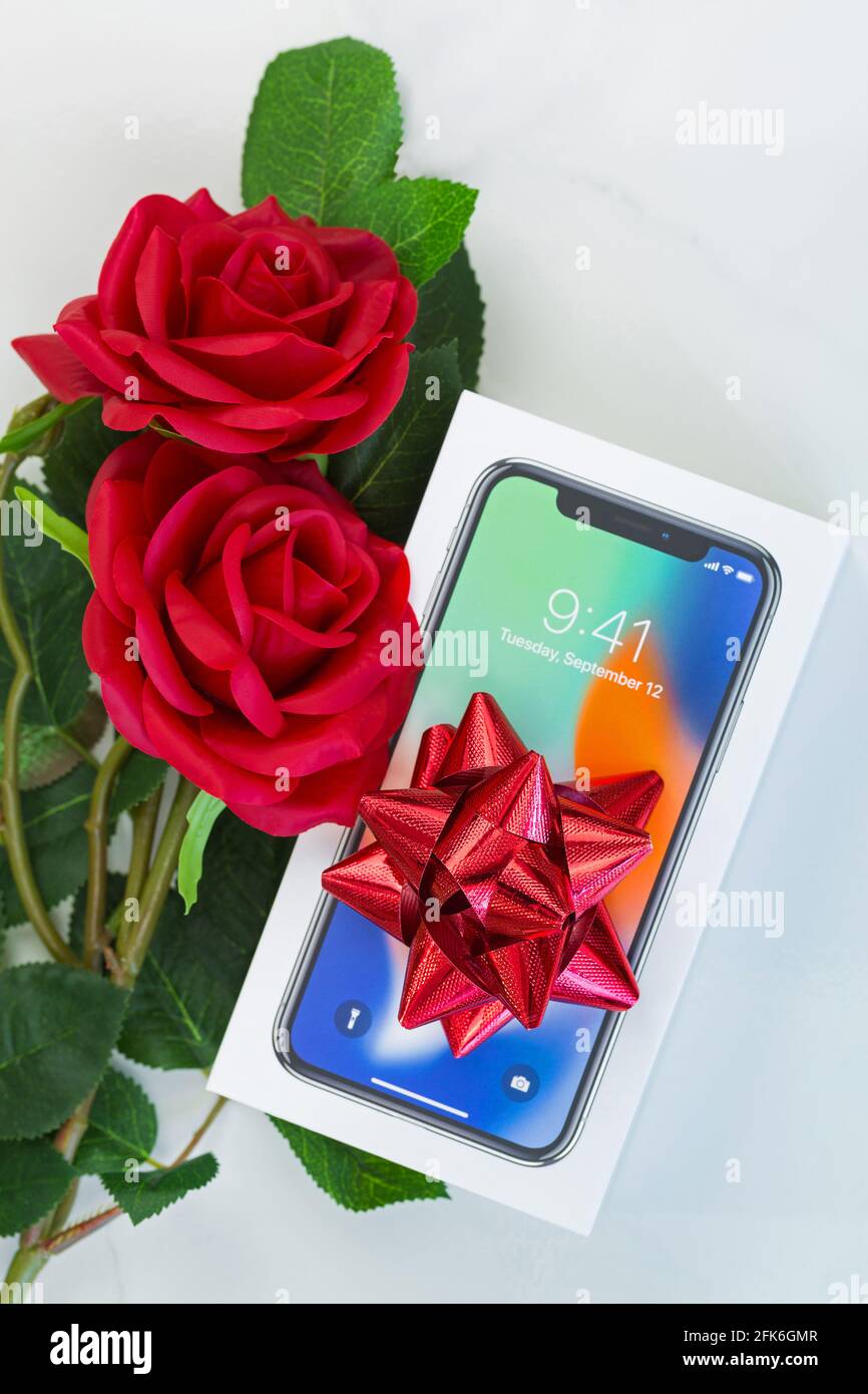 BANGKOK, THAILAND - JANUARY 2018 : Box of new iPhone X (iPhone 10) with top view of red ribbon and red roses as a gift on marble background on January Stock Photo