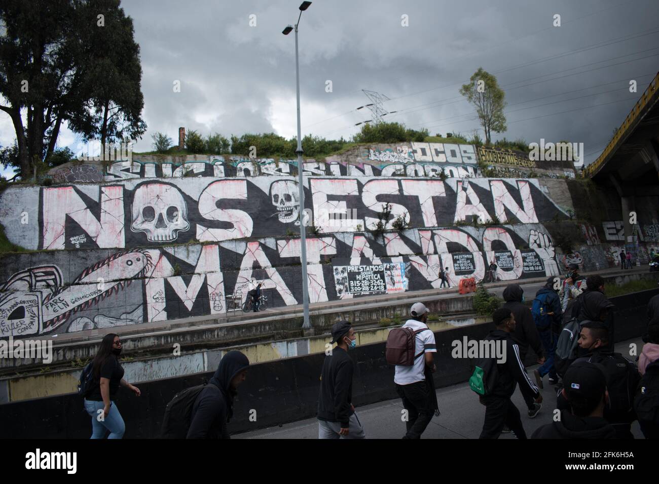 Bogota, Cundinamarca, Colombia. 28th Apr, 2021. Demonstrators pass in front of a mural depicting Colombian massacres as demonstrations rise against the tributary reform of president Ivan Duque on April 28, 2021, demonstrations rised to clashes between police and demonstrators. Credit: Daniel Santiago Romero Chaparro/LongVisual/ZUMA Wire/Alamy Live News Stock Photo