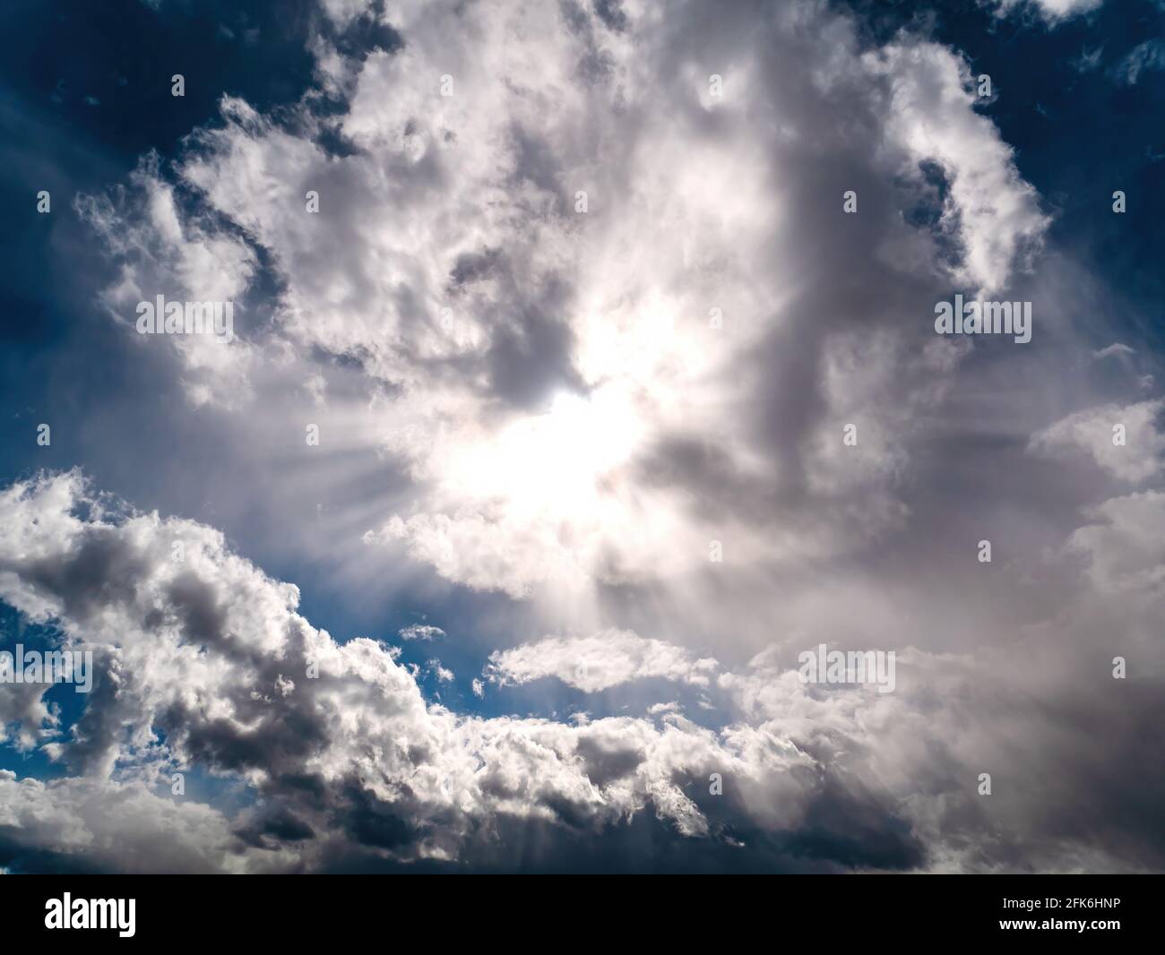 Sun rays shining through the clouds on the blue sky. Sunlight. Blue sky. Cloudy landscape. Overcast. Atmospheric phenomenon. Weather forecast. Backgro Stock Photo