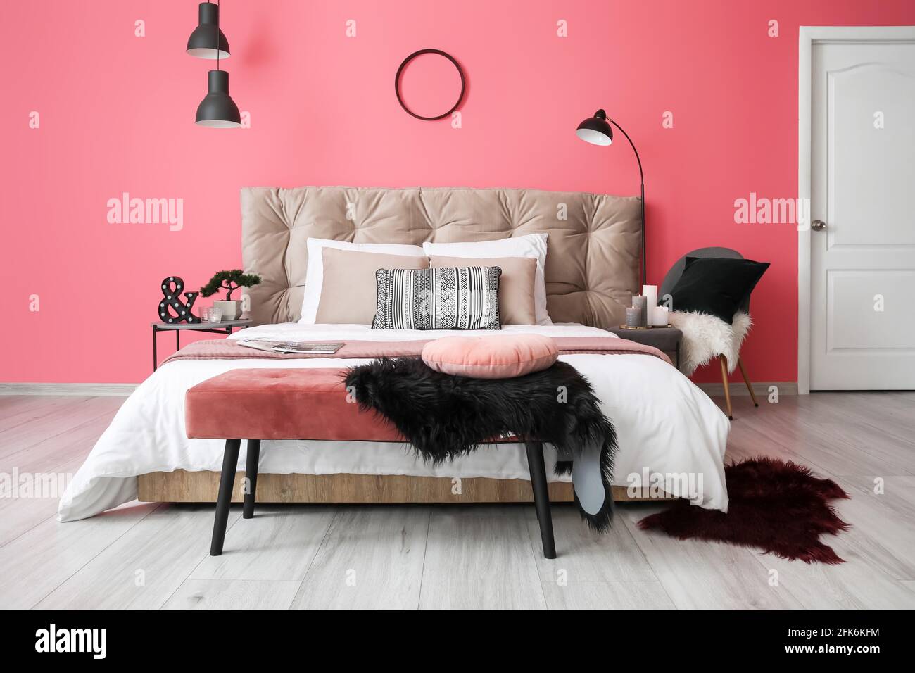 Stylish interior of modern bedroom with floor lamp and burning candles