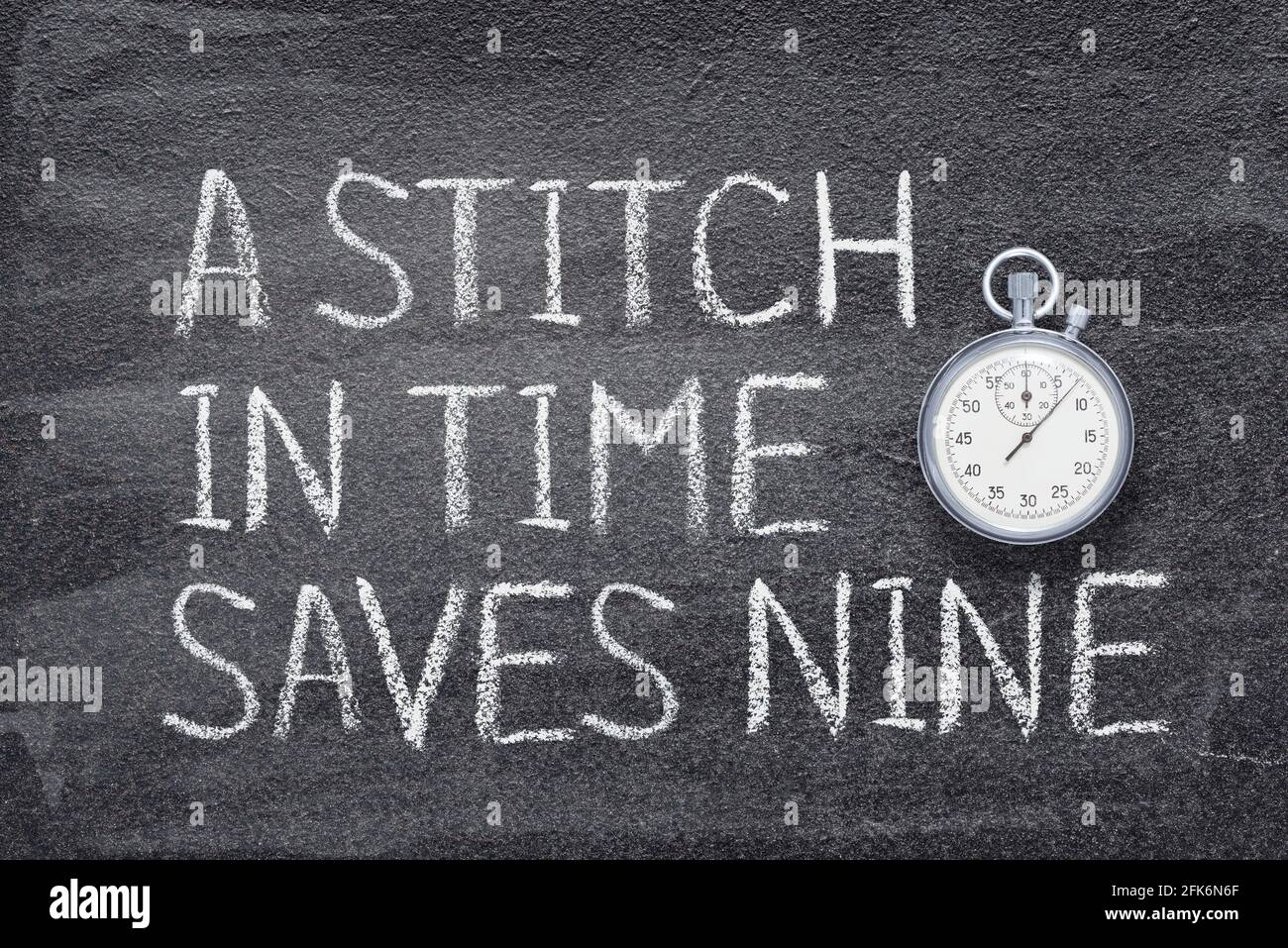 A stitch in time saves nine saying written on chalkboard with vintage precise stopwatch Stock Photo