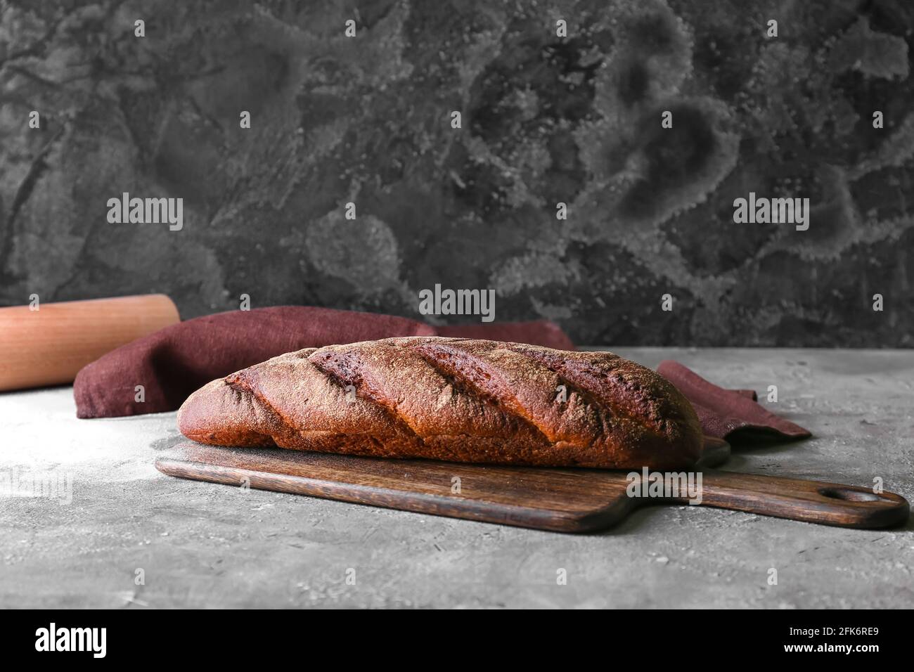 Board with fresh bread on grey background Stock Photo - Alamy