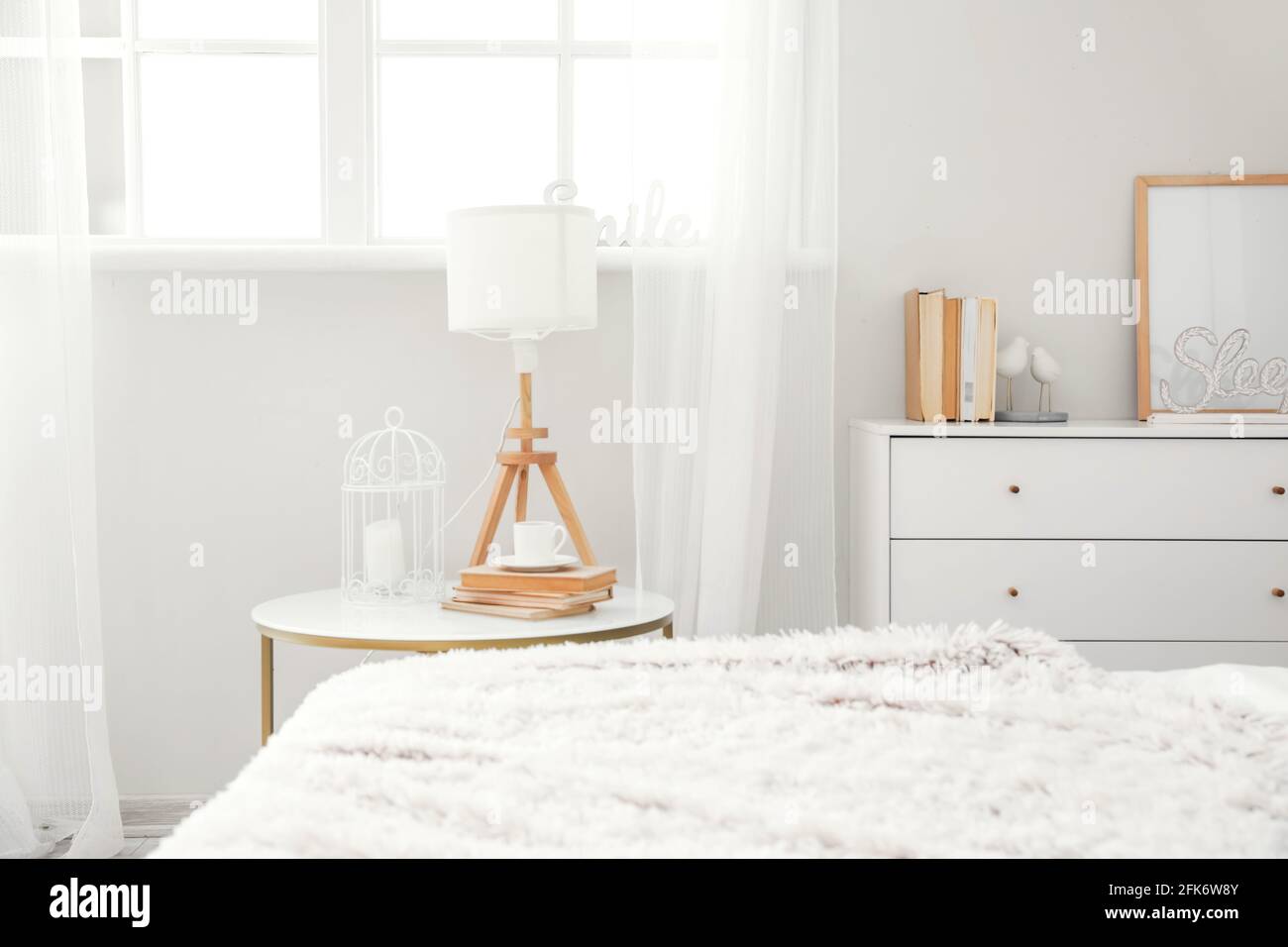 Bedside table with lamp and cup of coffee in interior of modern room ...