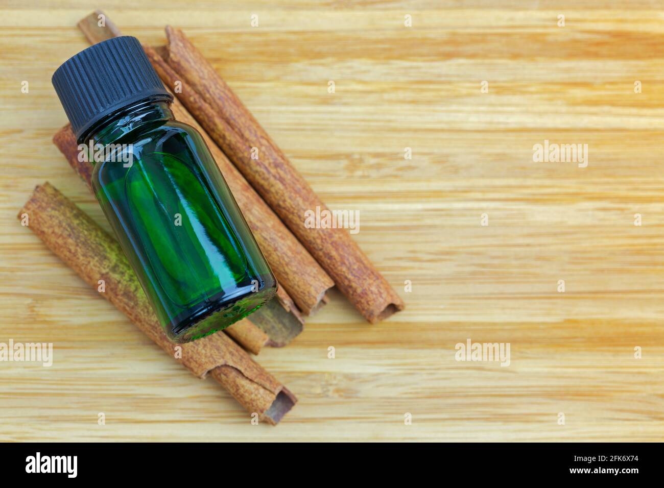 Pure Cinnamon essential concentrate oil extract in green bottle on Cinnamon sticks on wooden background with copyspace Stock Photo