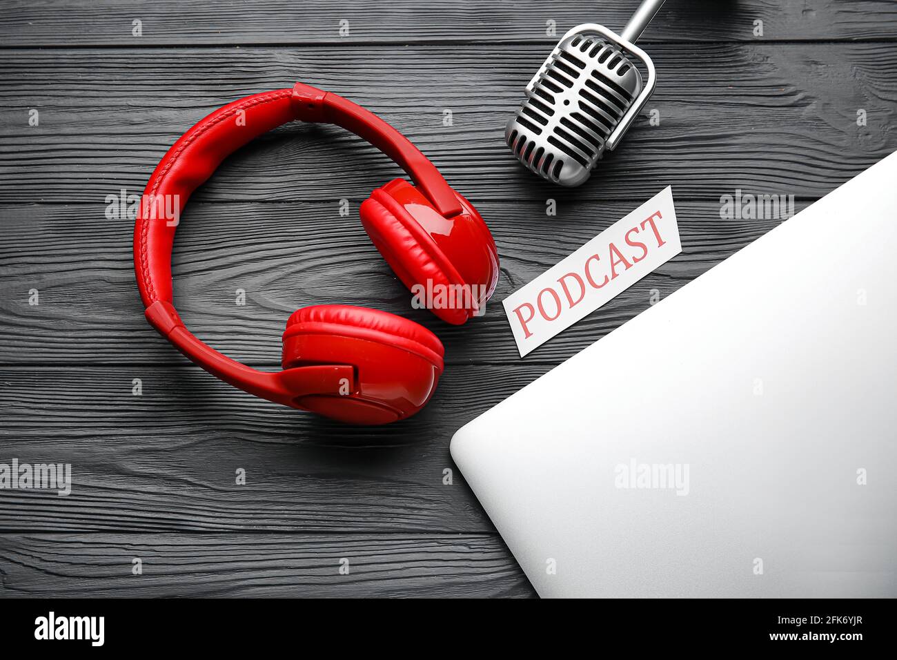Microphone with headphones and laptop on dark wooden background Stock