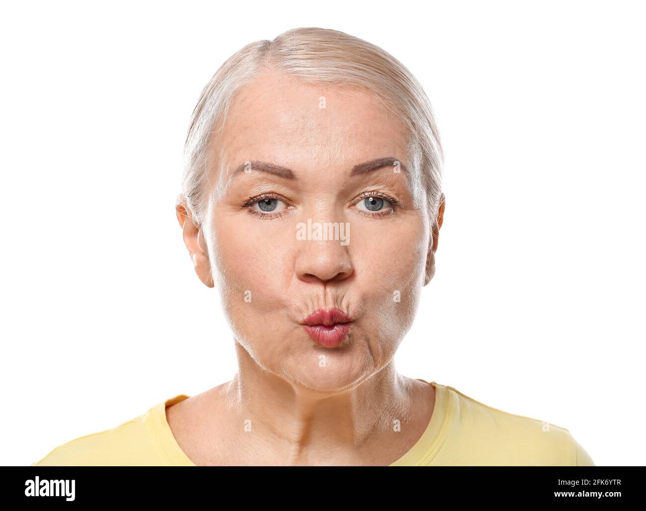 Mature woman doing face building exercises against white background