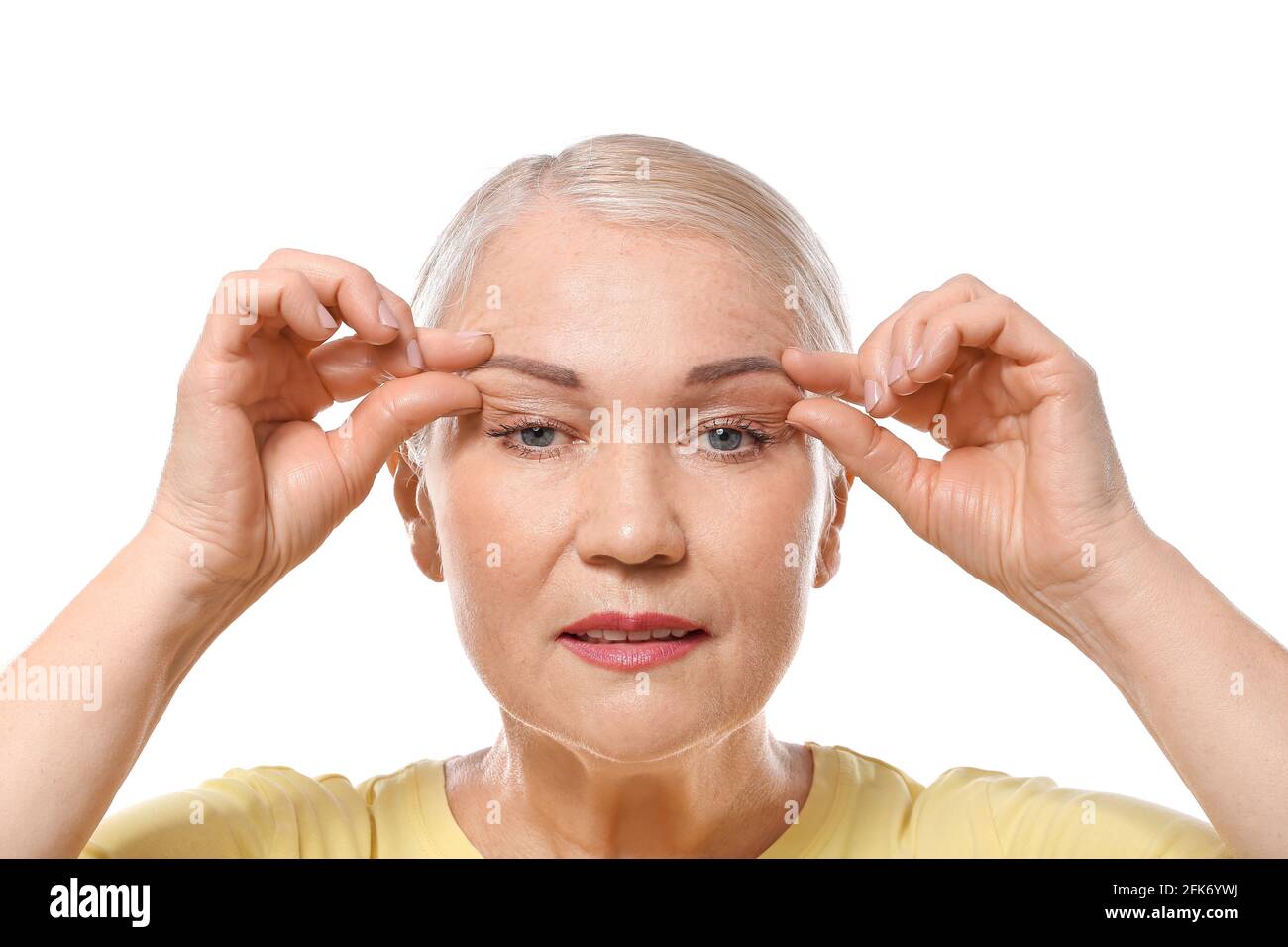Mature woman doing face building exercises against white background