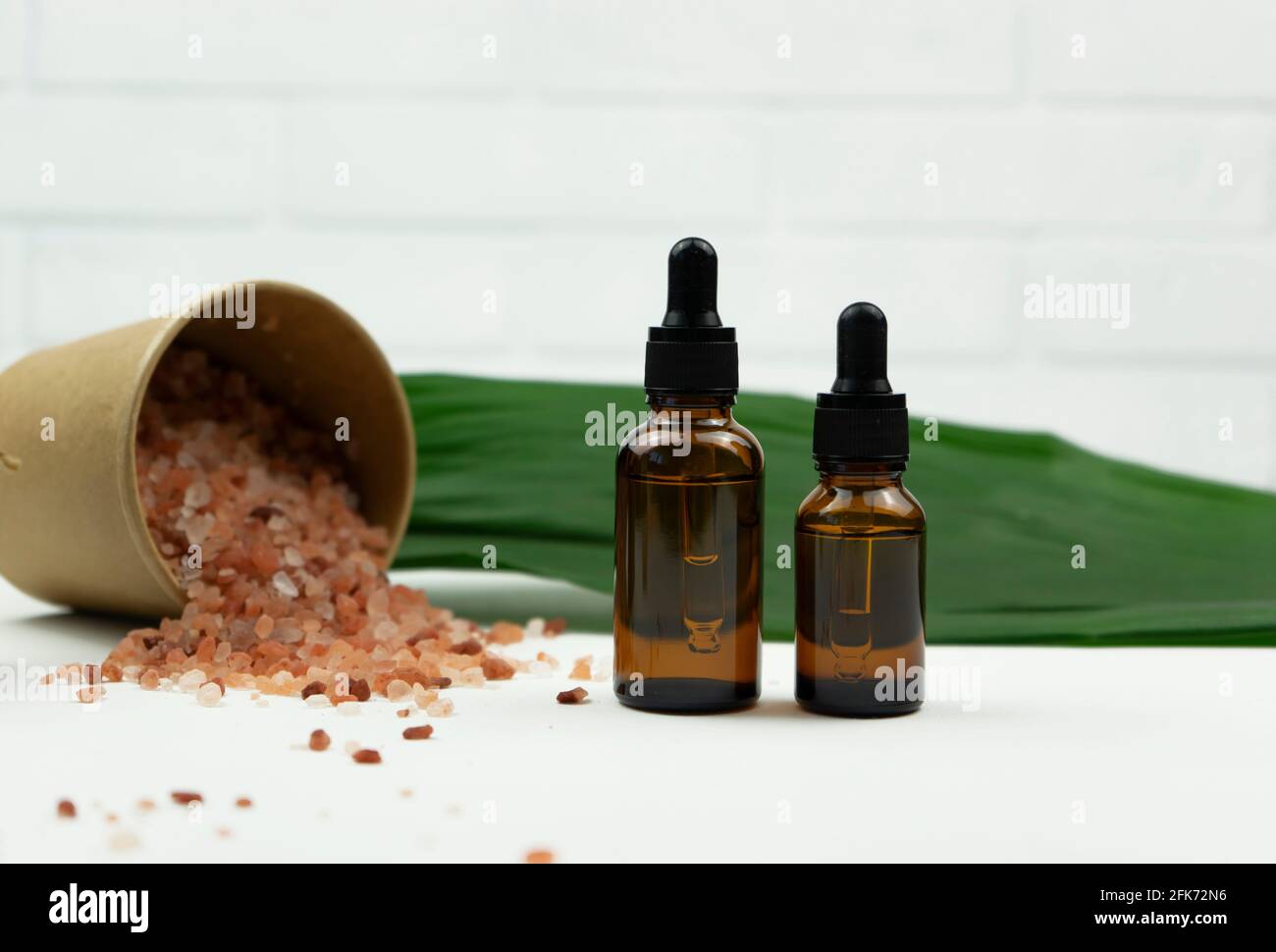 Two dropper bottles of hyaluron serum stand on a white table in a modern bathroom Stock Photo