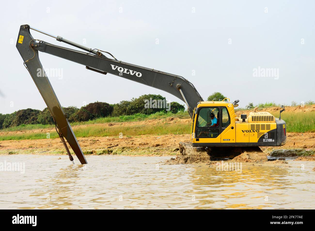 A Volvo Excavator taking out muddy earth from the shore of Tonle Sap lake in Cambodia. Stock Photo