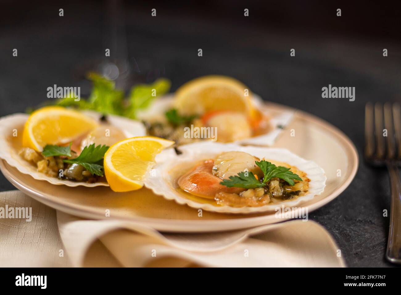 Baked scallops with caviar in a plate against the background. Scallops