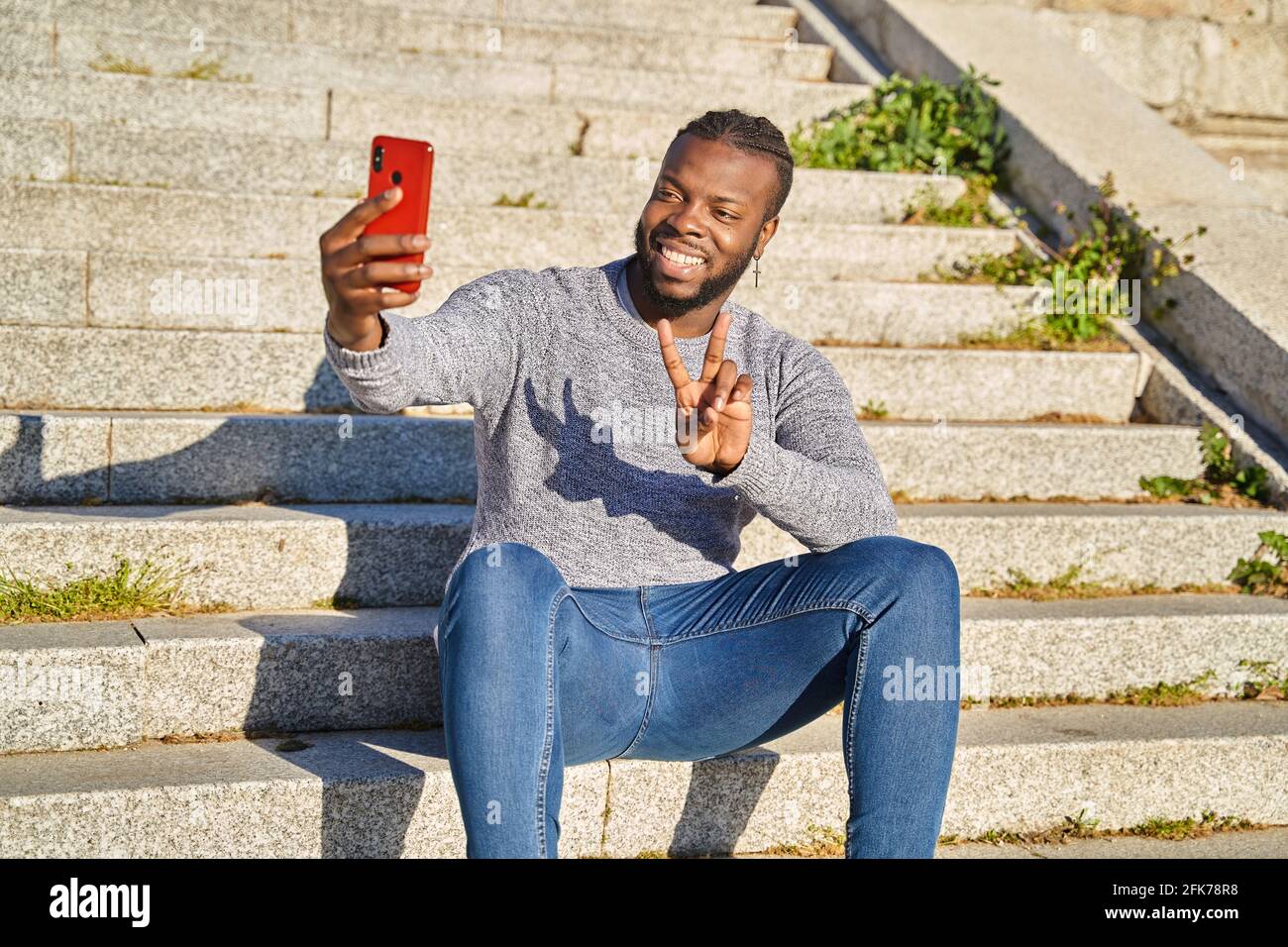Young African American man sitting on the stairs taking a self-portrait ...