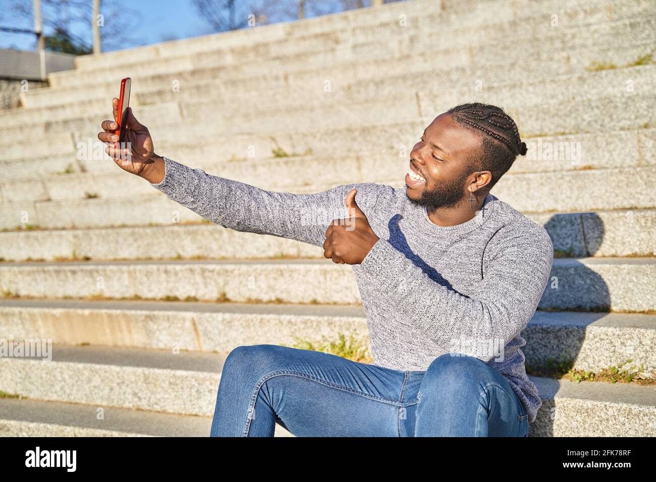 Young African American man sitting on the stairs taking a self-portrait ...
