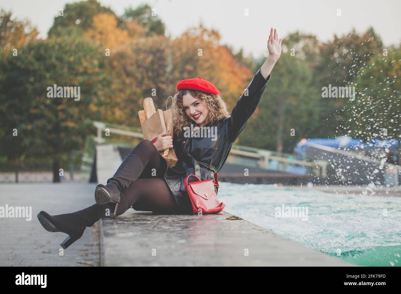 Pretty young woman in red beret holding craft paper bag with fresh french baguette Stock Photo