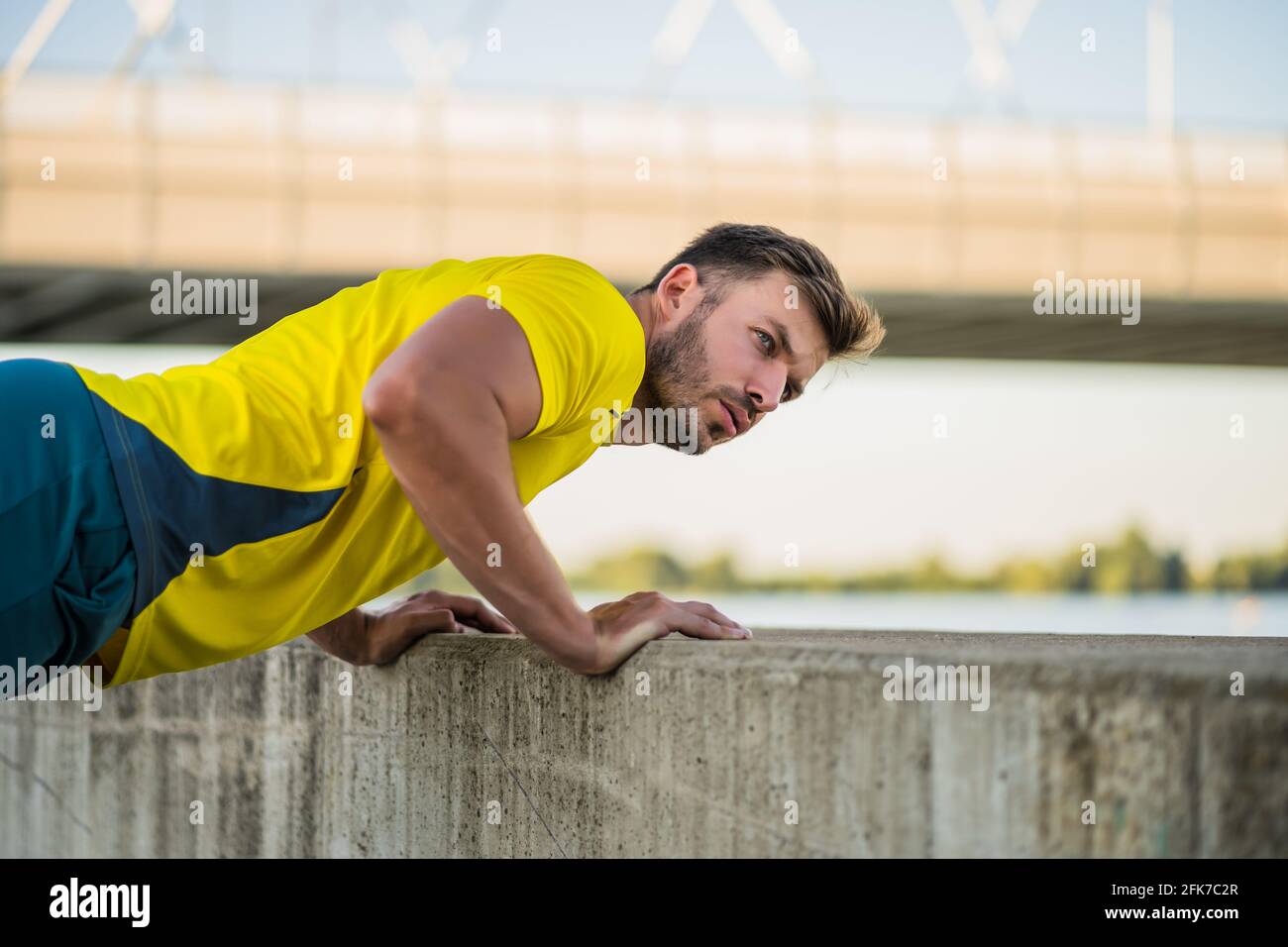 Young man is exercising outdoor. He is doing push-ups. Stock Photo