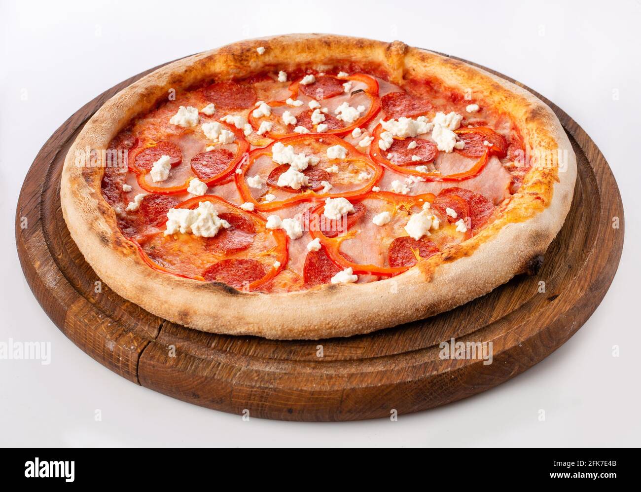 Top view of hot pizza on a wooden stand. Pizza 4 seasons . Made on tomatoes, with spicy salami, tender ham, and complements with shades of sweet peppe Stock Photo