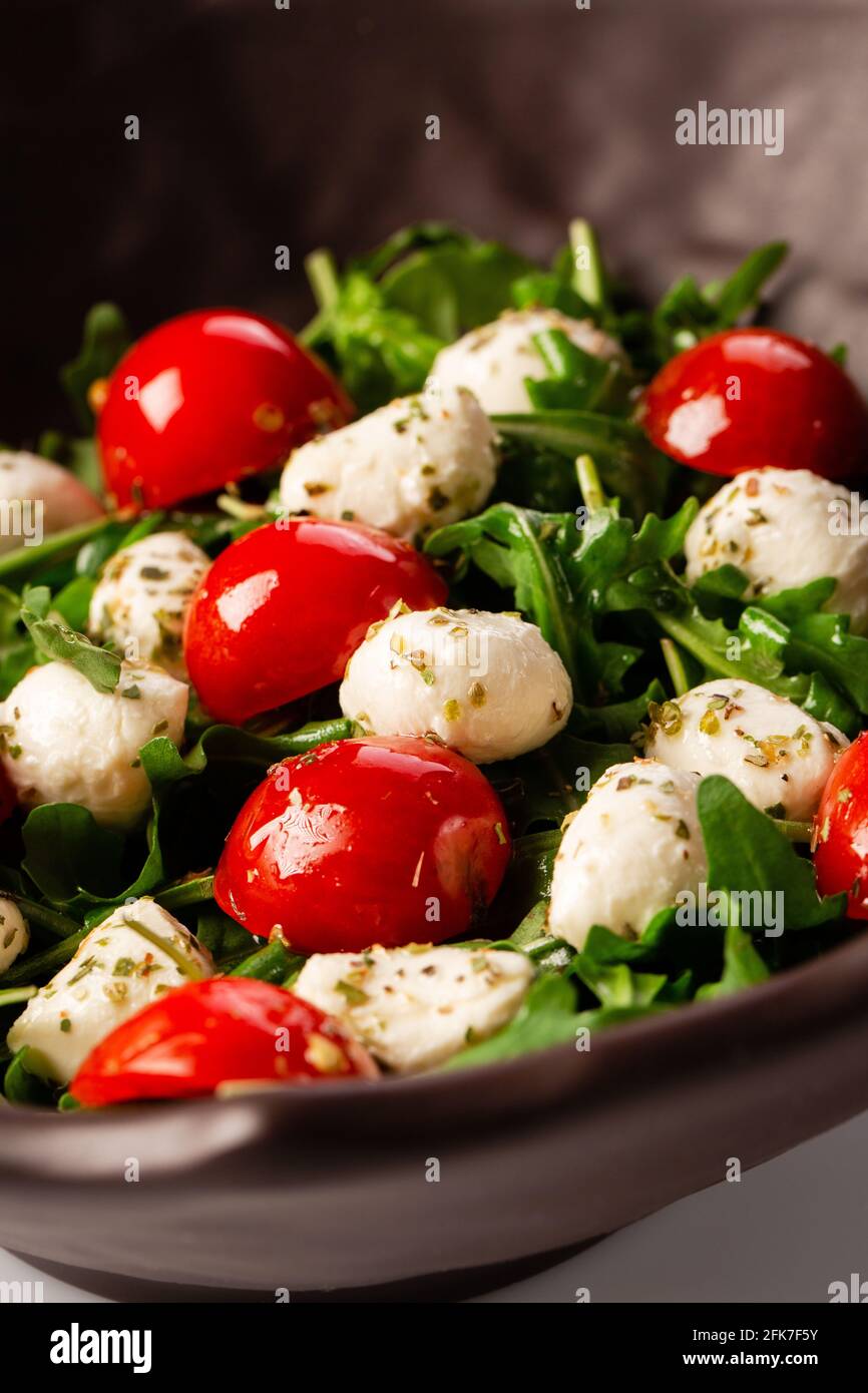 Caprese salad. Fresh arugula, cherry tomatoes, juicy mini mozzarella and a dressing of oregano and olive oil Stock Photo
