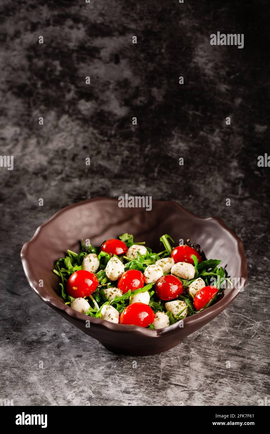 Caprese salad. Fresh arugula, cherry tomatoes, juicy mini mozzarella and a dressing of oregano and olive oil Stock Photo