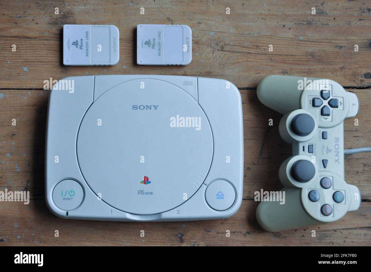 Sony Playstation One Slim with memory cards and controller on wooden table background Stock Photo