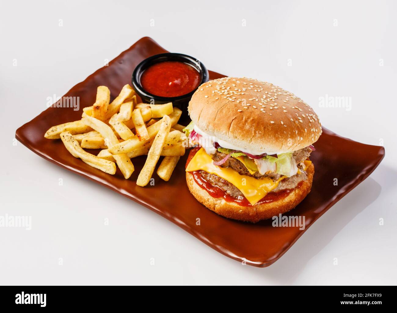 Burger. Juicy pork cutlet, cheddar cheese, crispy pickled onions, lettuce wrapped in a bun under two sauces. Served with french fries and cream sauce. Stock Photo