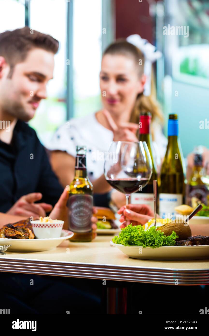 Friends or couples eating fast food and drinking beer and wine in a