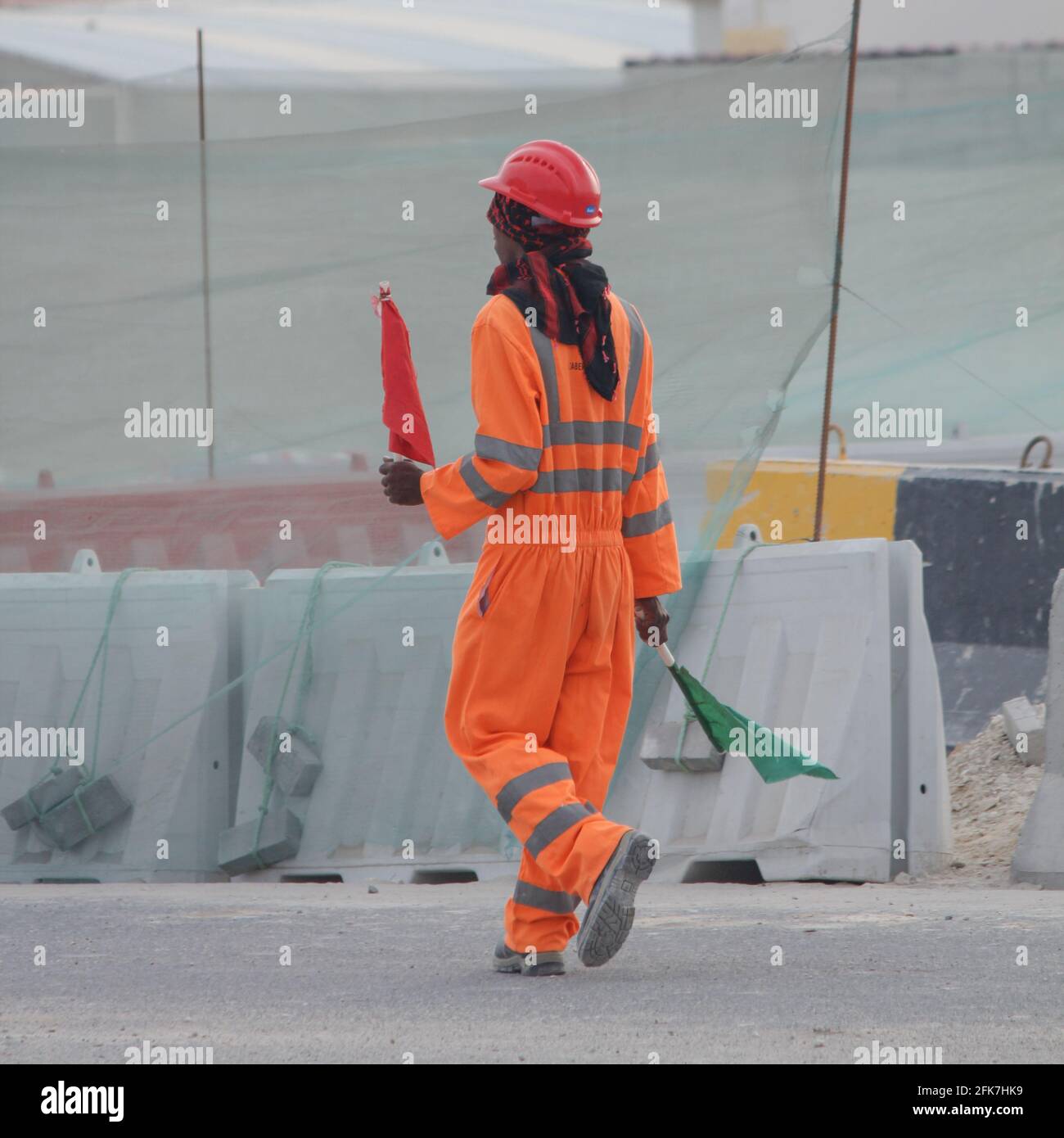 A construction worker with green and red flag guiding the excavator driver. Stock Photo