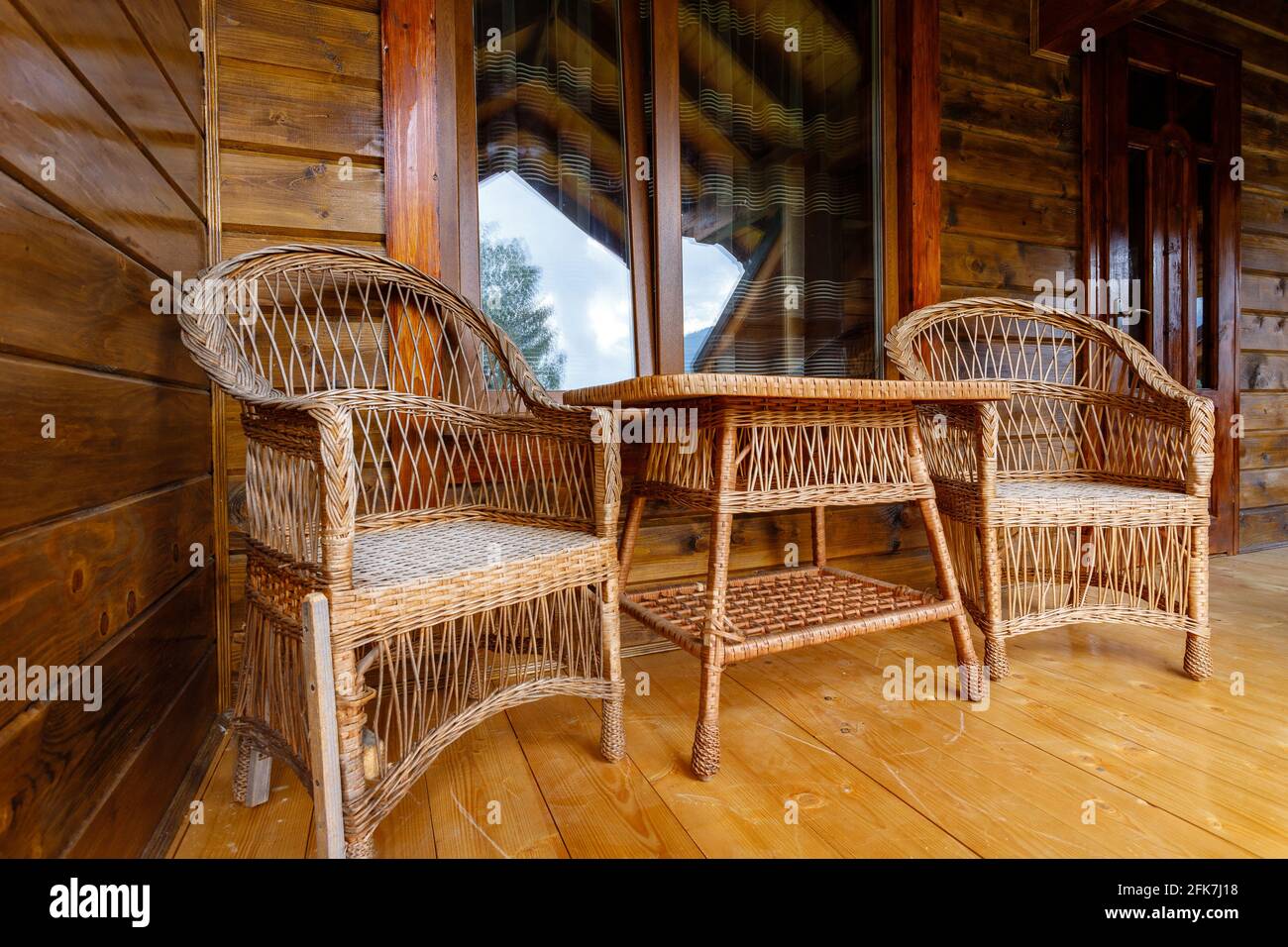 Beautiful outdoor terrace with wicker table and two armchairs on wooden ...