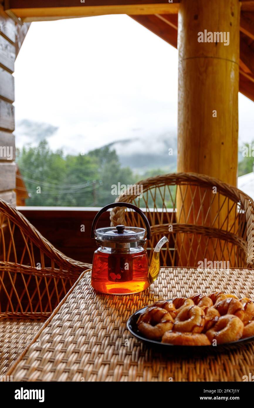 Time for hot herbal tea in a glass teapot on a small rattan table on