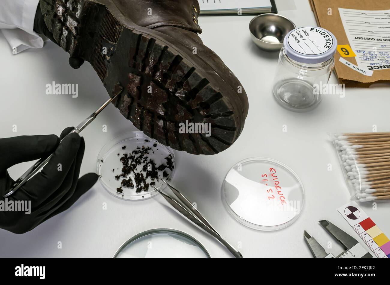 Specializing police officer analyzes ground in a victim's shoe murder with one tweezers, conceptual image Stock Photo
