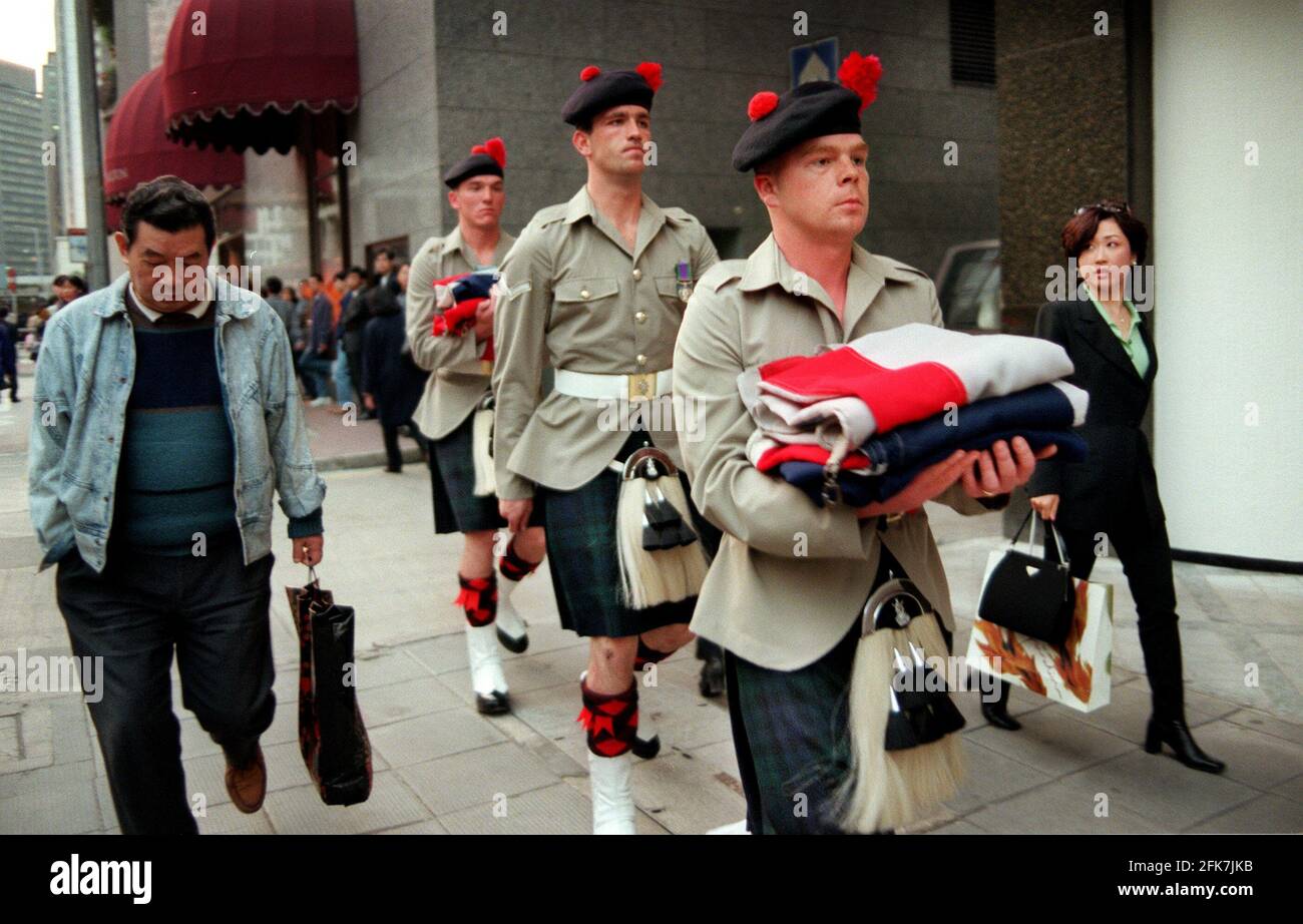 BRITISH FLAGS ARE CARRIED BACK TO BARRACKS  BY THE BLACK WATCH AFTER  BEING LOWERED AT SIX IN THE EVENING  ONE OF MANY BRITISH ECCENTRICITIES GREETED WITH A MIXTURE OF AMUSEMENT BEWILDERMENT AND INDIFERENCE BY THE CHINESE Stock Photo