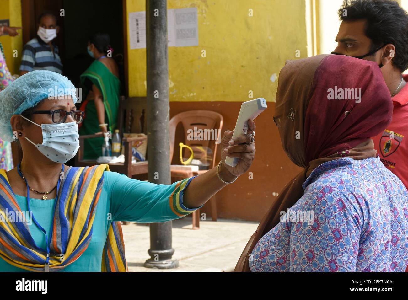 Kolkata, India. 29th Apr, 2021. A vote worker taking body temperature by thermal screening before enter the Polling Booth at Kolkata, West Bengal. (Photo by Suraranjan Nandi/Pacific Press) Credit: Pacific Press Media Production Corp./Alamy Live News Stock Photo
