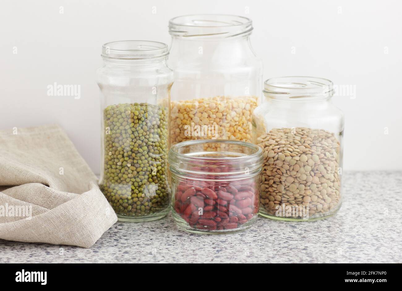 Variety of dry legumes: kidney bean, peas, green gram in glass jars uncooked on white kitchen background, zero waste, eco friendly, balanced diet food Stock Photo