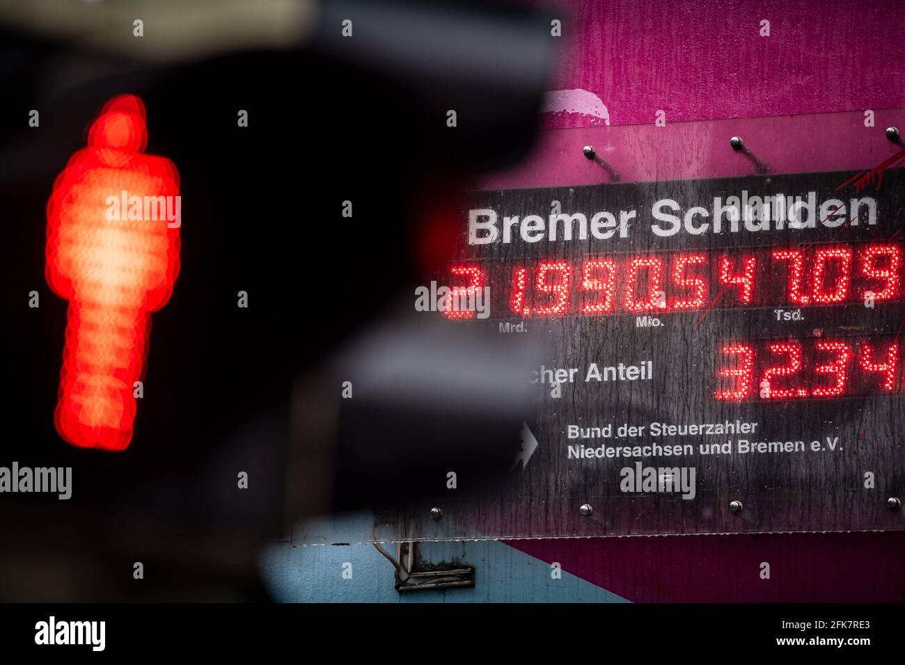 Bremen, Germany. 29th Apr, 2021. A red traffic light shines in front of the Bremen debt clock. The BdSt debt clock was programmed for the year 2021. Credit: Sina Schuldt/dpa/Alamy Live News Stock Photo
