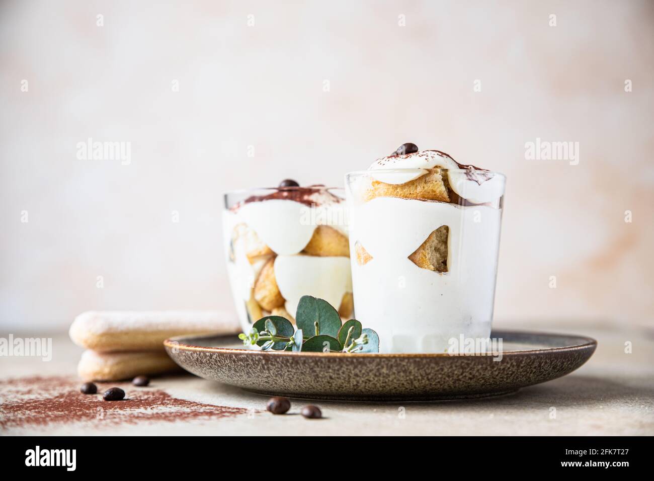 Traditional Italian dessert tiramisu in glass, light stone background